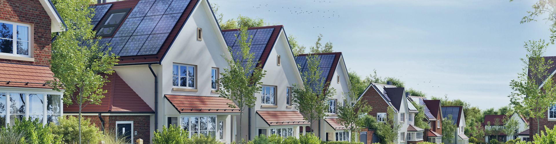 a row of houses with solar panels on the roofs .