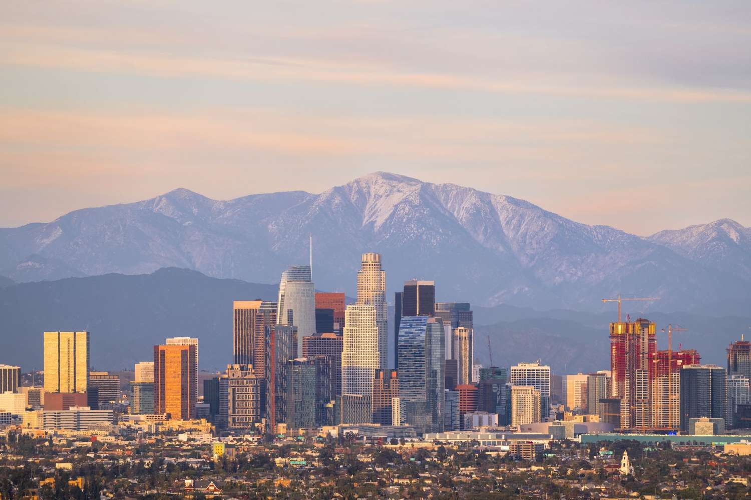 An aerial view of a city skyline with mountains in the background.