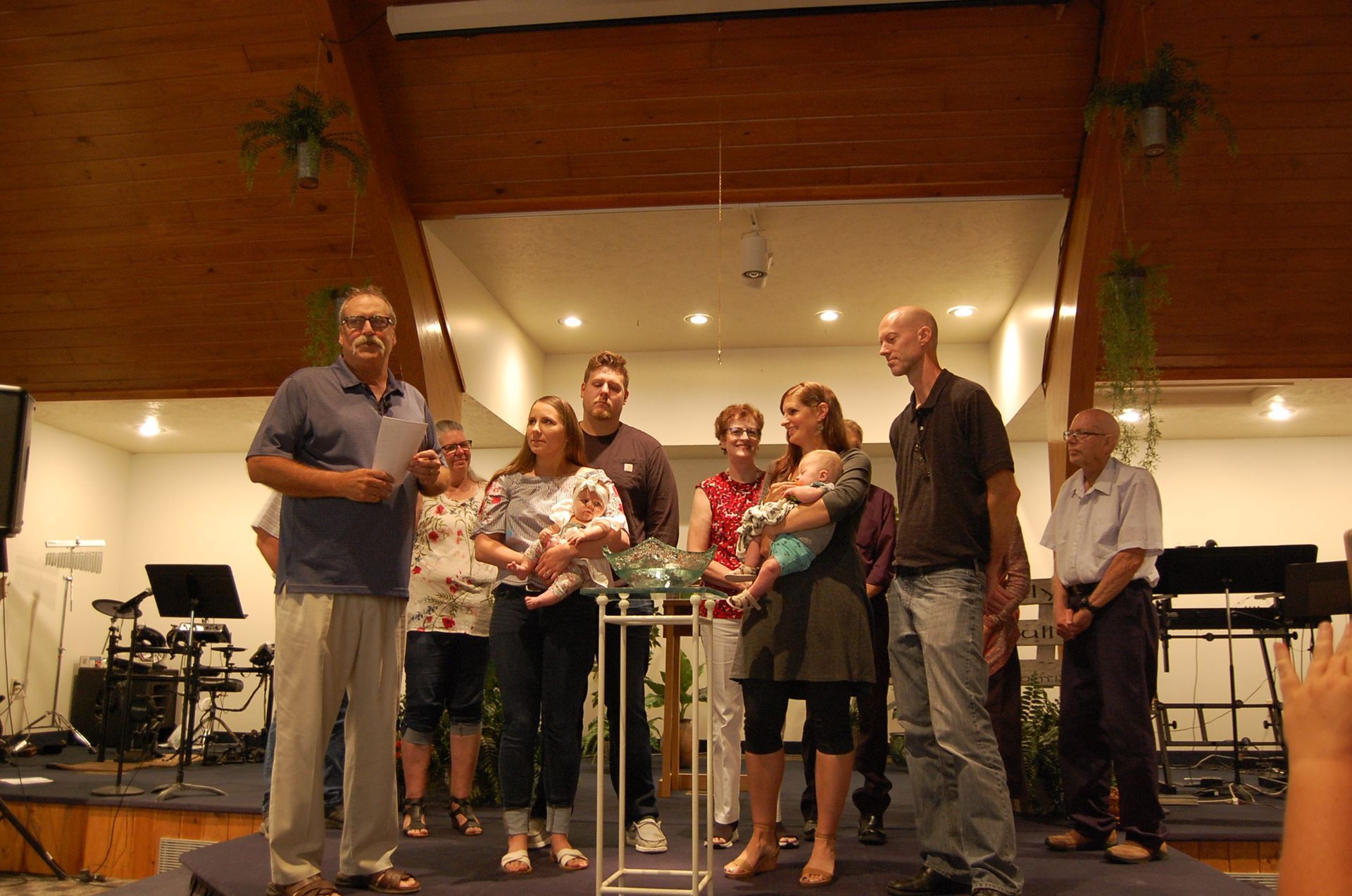 A group of people standing on a stage including a man holding a baby.
