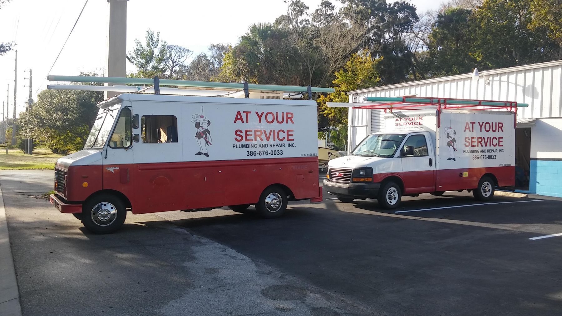 Two red and white service trucks are parked next to each other