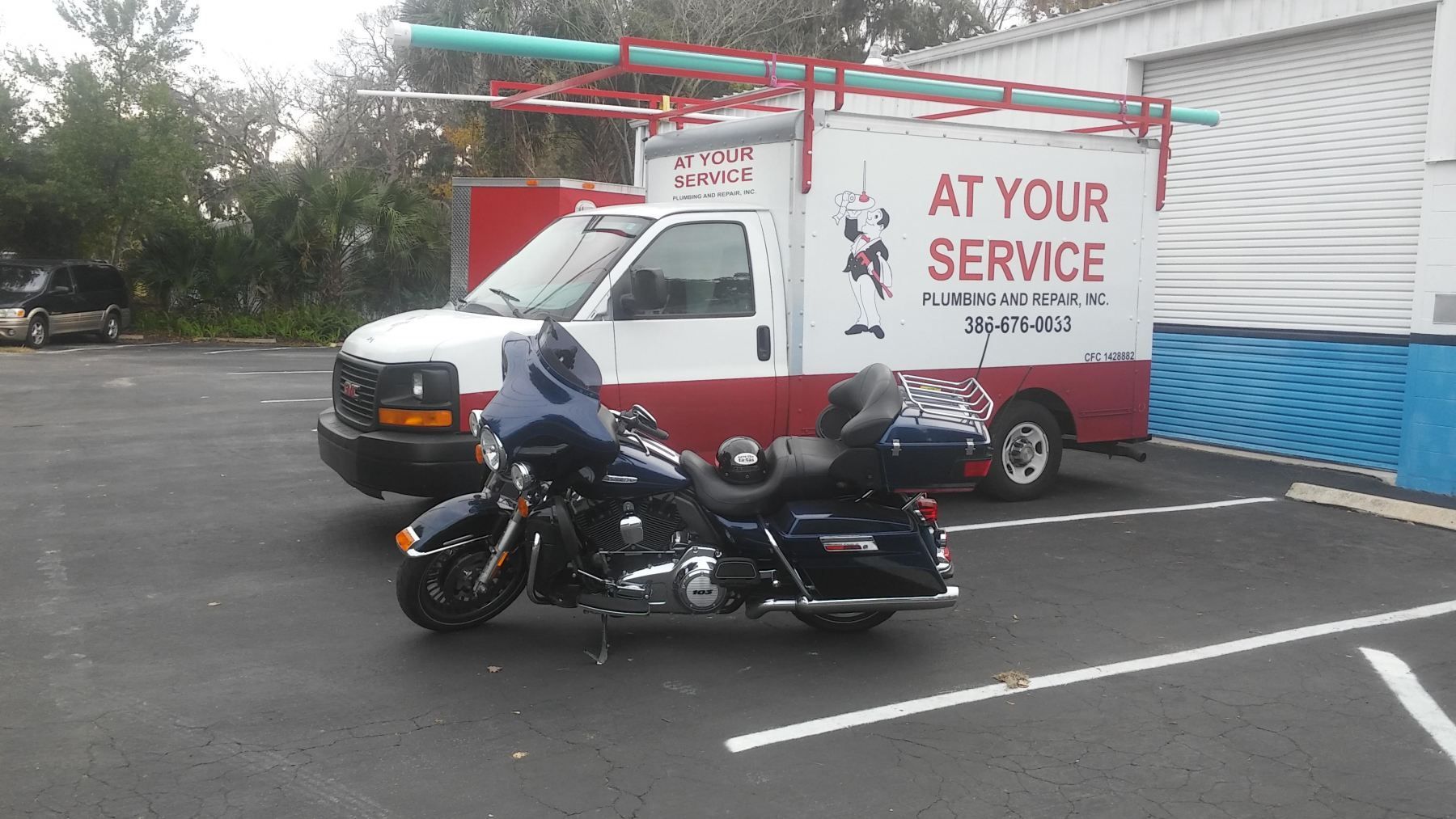 A motorcycle is parked in front of a truck that says at your service