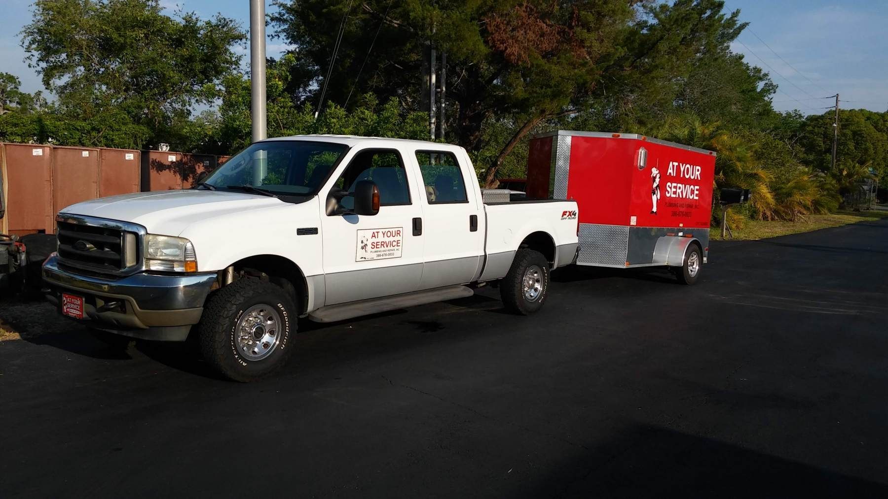 A white truck with a red trailer attached to it