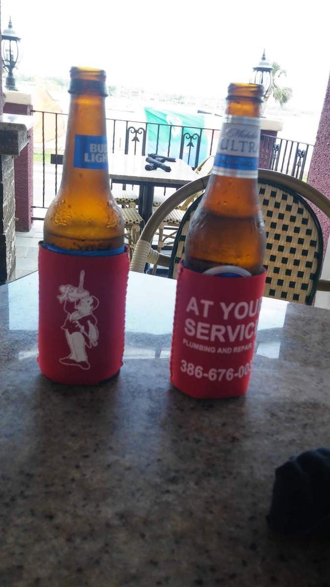 Two bottles of beer on a table with one that says at your service