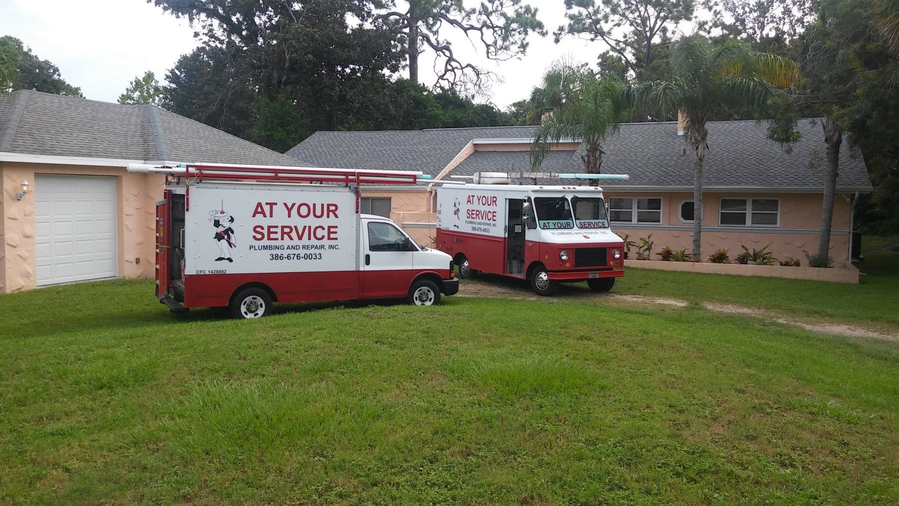 Two at your service trucks are parked in front of a house
