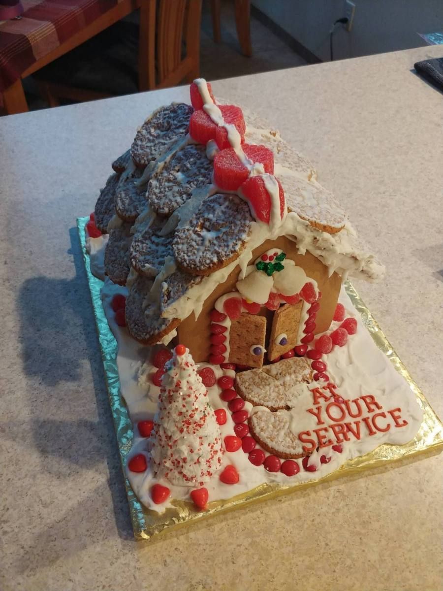 A gingerbread house that says at your service on it