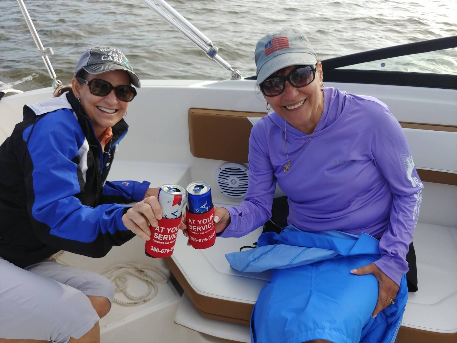 Two women are sitting on a boat toasting with pepsi cans