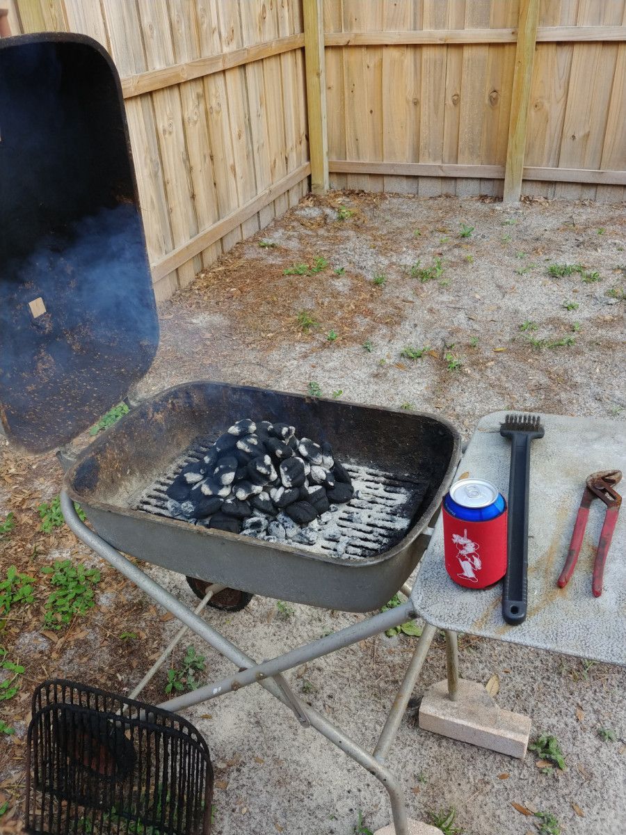 A grill is sitting on a table next to a can of soda and a pair of pliers.