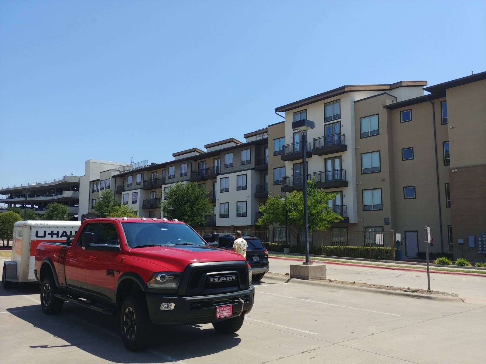 A red ram truck is parked in front of a large apartment building