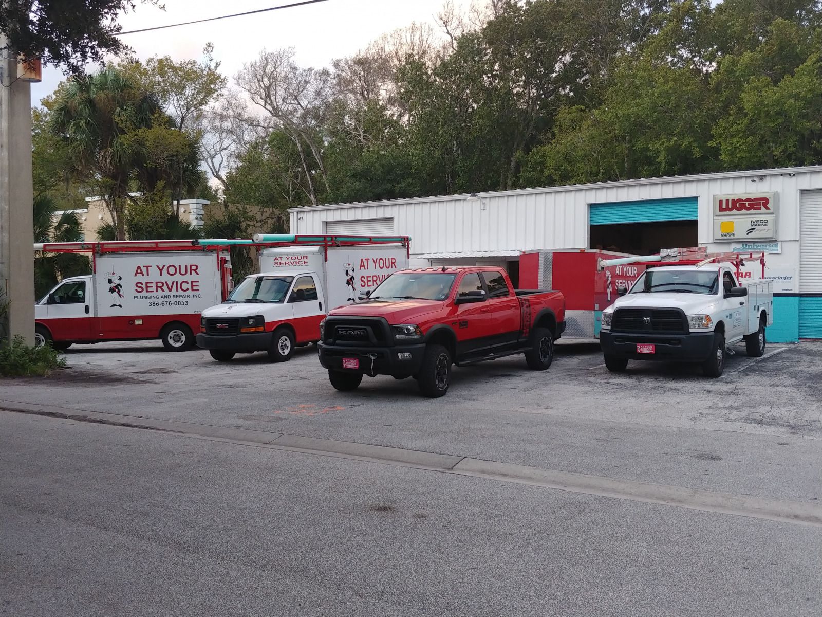 A row of trucks parked in front of a building that says at your service