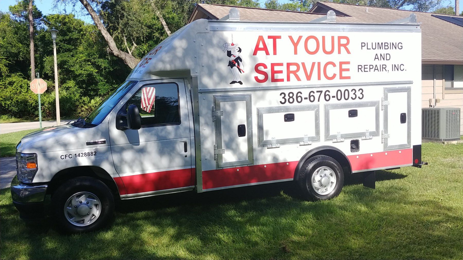 A white and red van with the words `` at your service '' on the side is parked in front of a house.