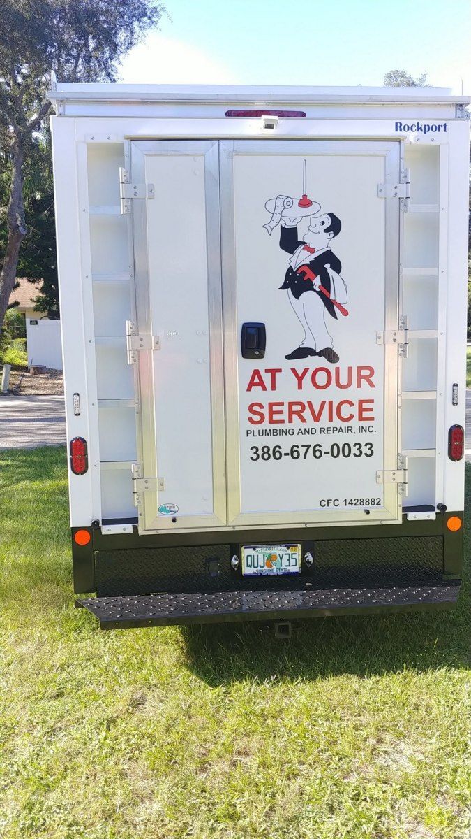 The back of a white truck that says at your service