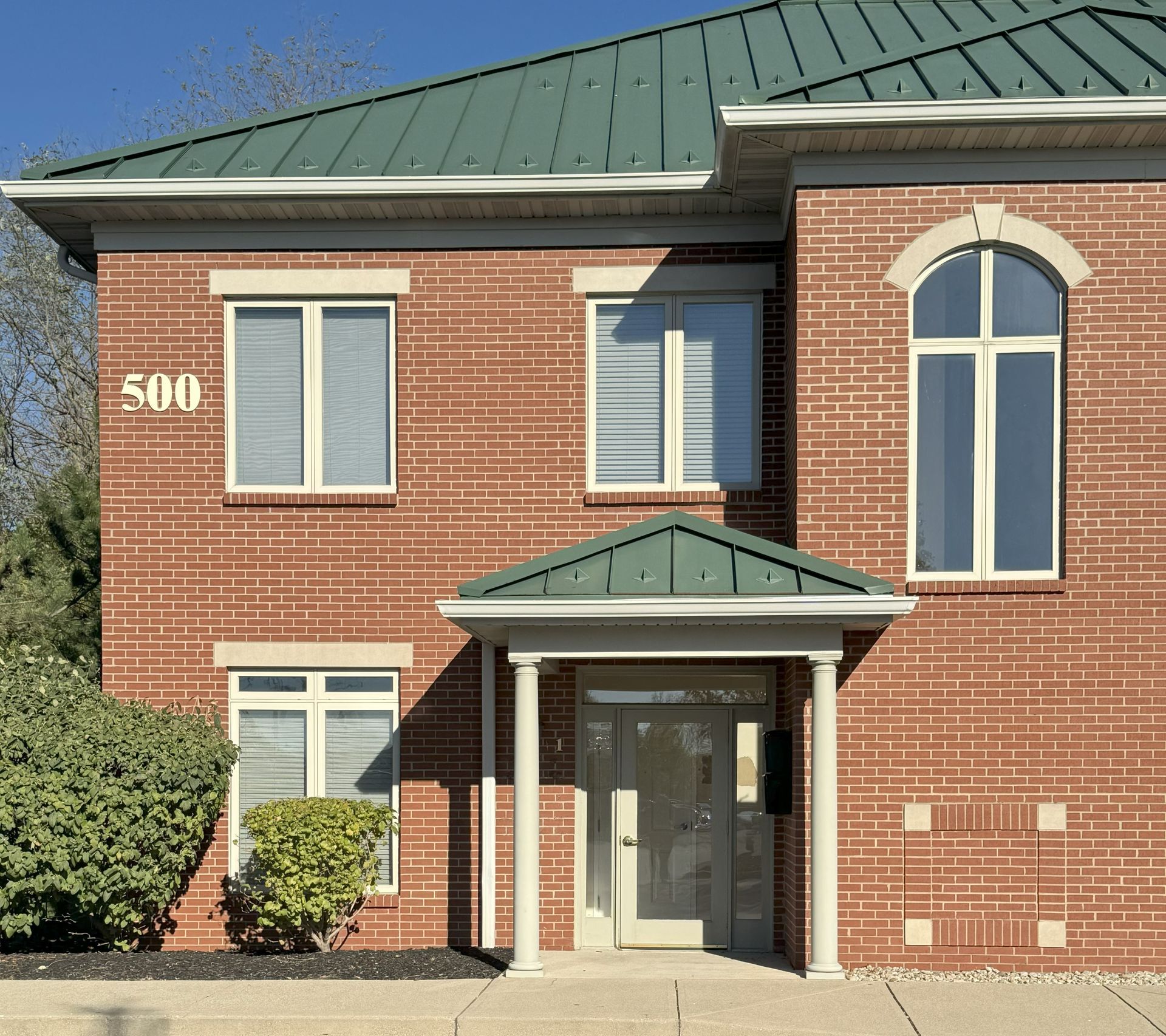 Two-story brick building with green roof, columns at entrance; address 500. Two-story brick building with green roof, columns at entrance; address 500.