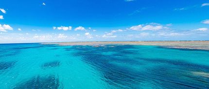 View of a large body of clear sea water with a blue sky in the background.