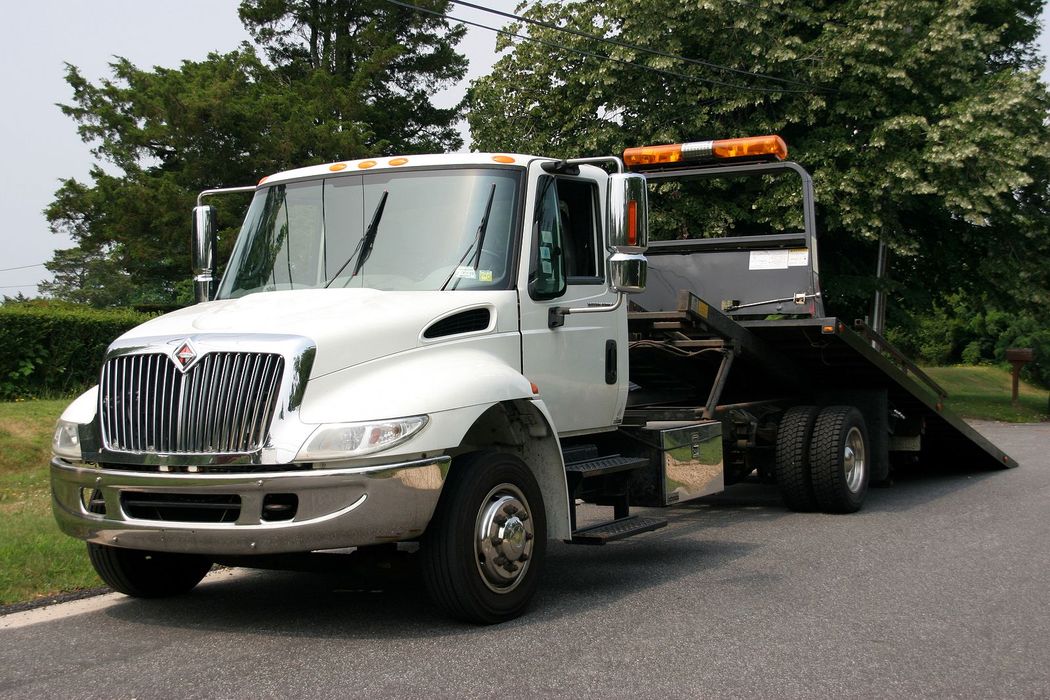 A white tow truck is parked on the side of the road