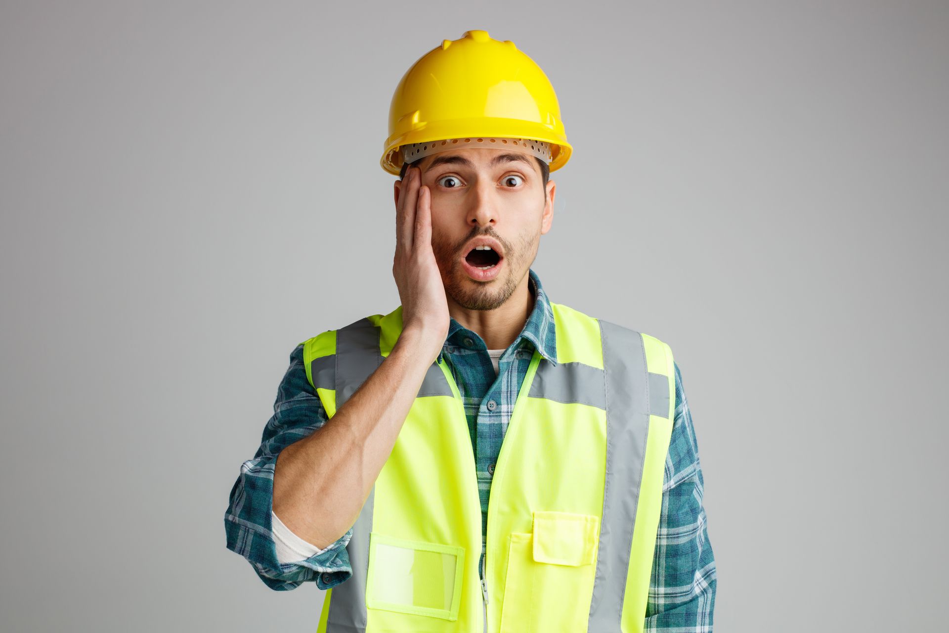 Construction worker wearing yellow hard hat and safety vest with surprised expression.