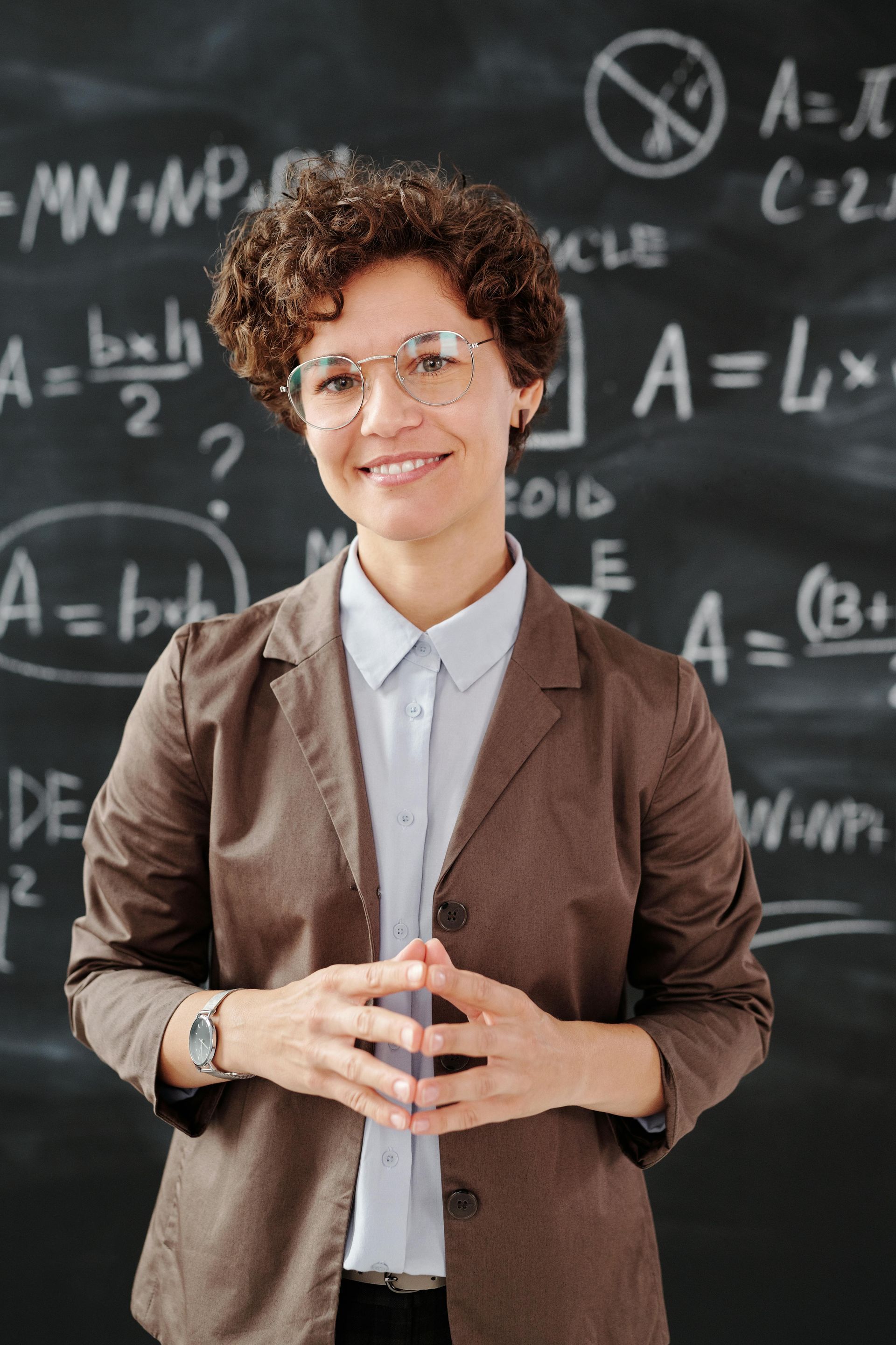 A woman is standing in front of a blackboard with equations on it