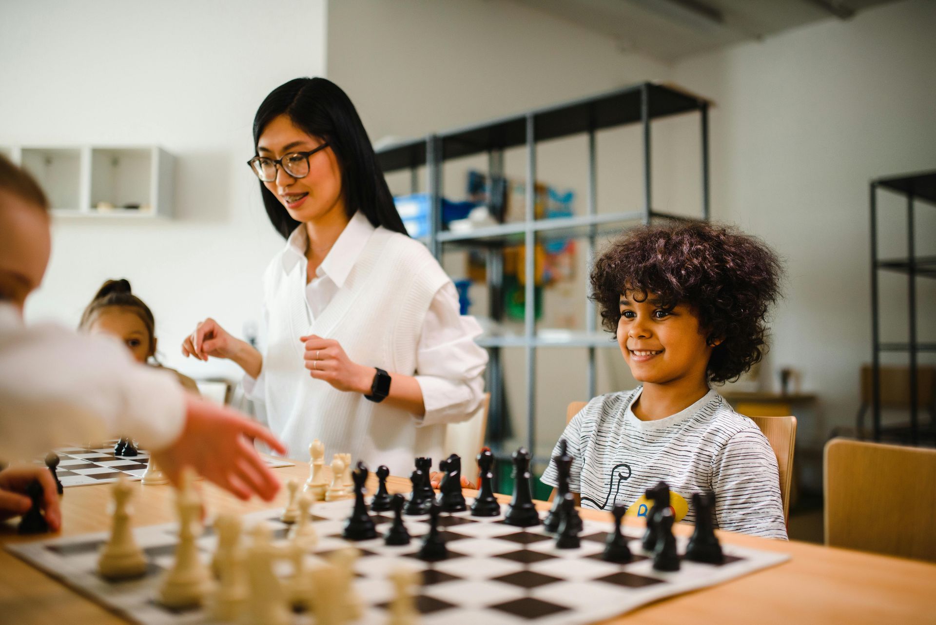 A woman is teaching a group of children how to play chess.