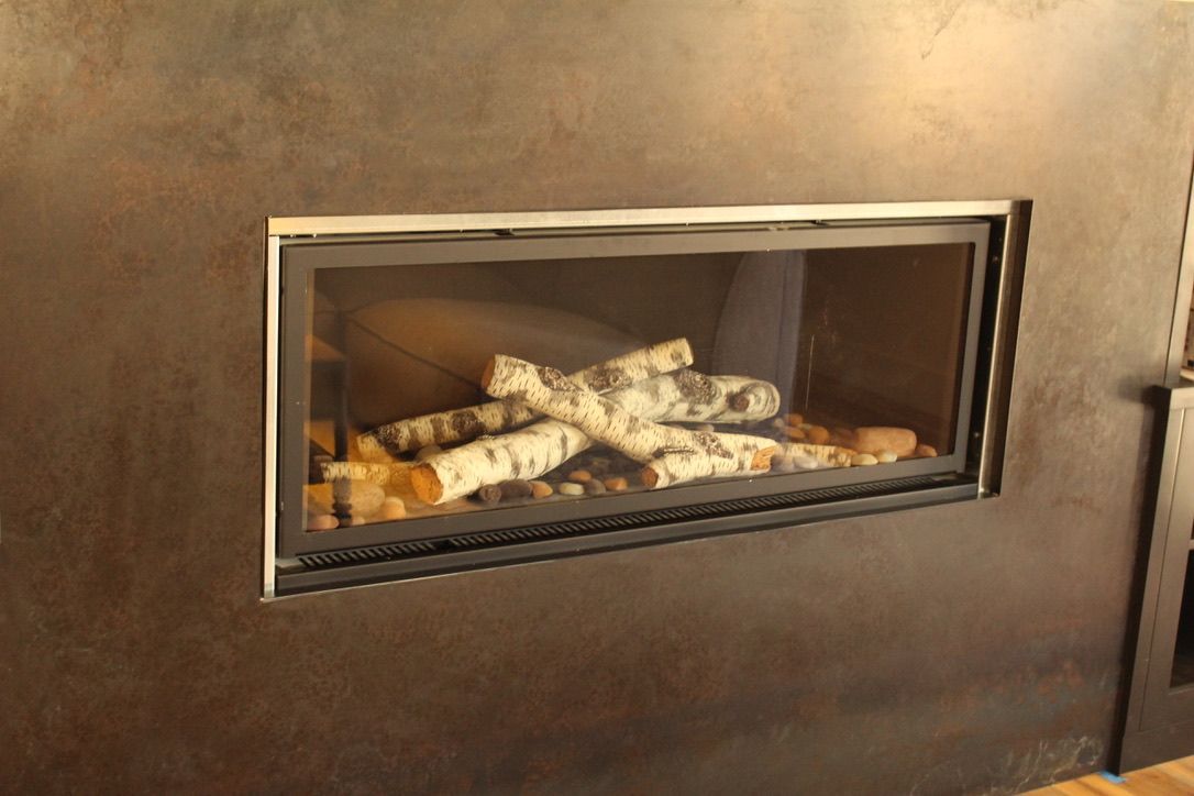 A fireplace with logs in it is built into a wall.
