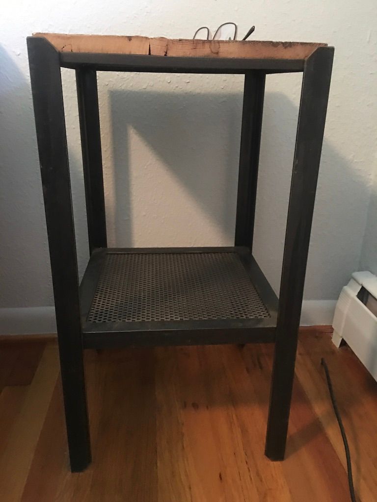 A small table with a wooden top and a metal shelf on a wooden floor.
