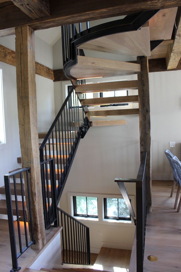 A wooden spiral staircase with a metal railing in a house.