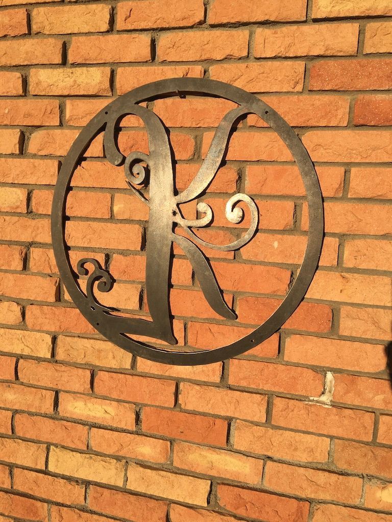The letter k is in a circle on a brick wall.