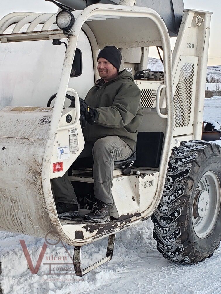 A man is sitting in a white vehicle in the snow