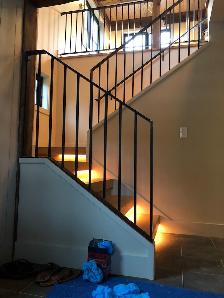 A staircase with a metal railing and lights on the steps