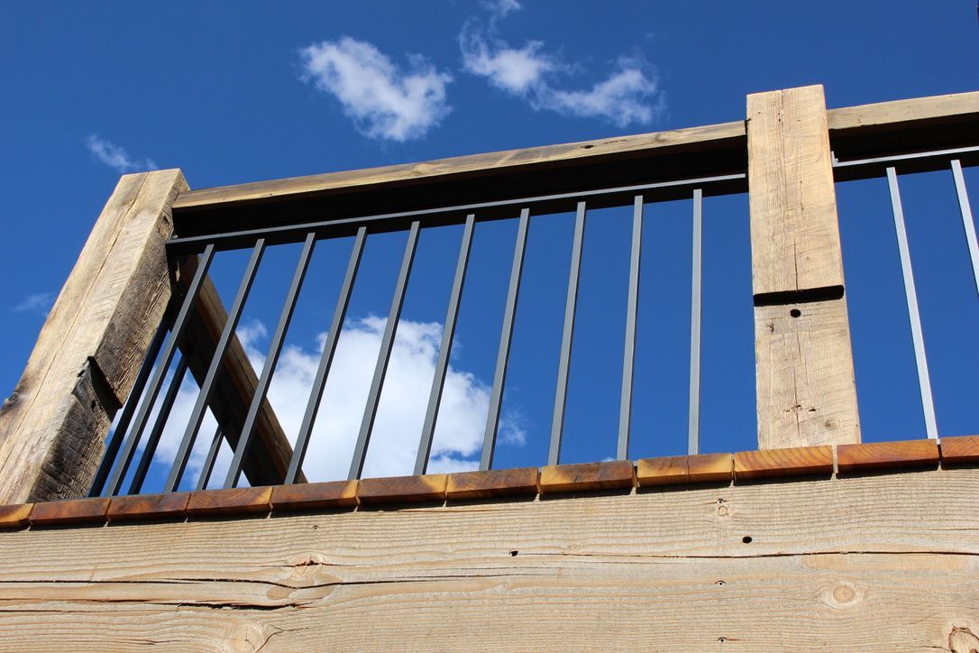 Looking up at a wooden railing with a blue sky in the background