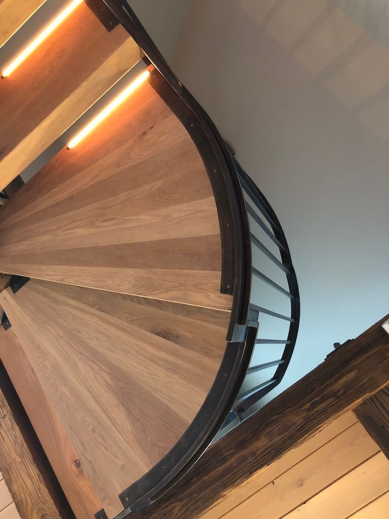 A spiral staircase with wooden steps and a metal railing