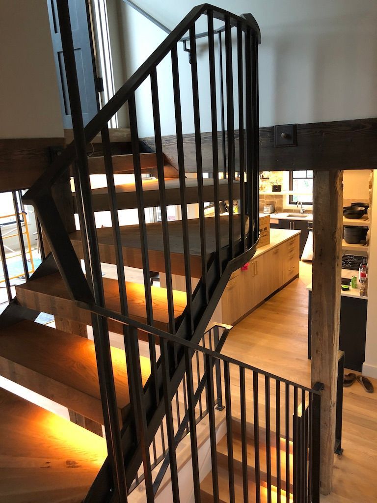 A wooden spiral staircase with a metal railing in a house.
