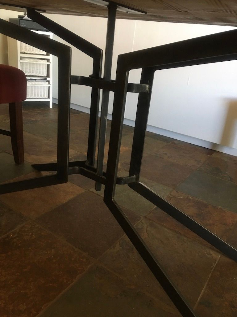 A table with a metal frame is sitting on a tiled floor.