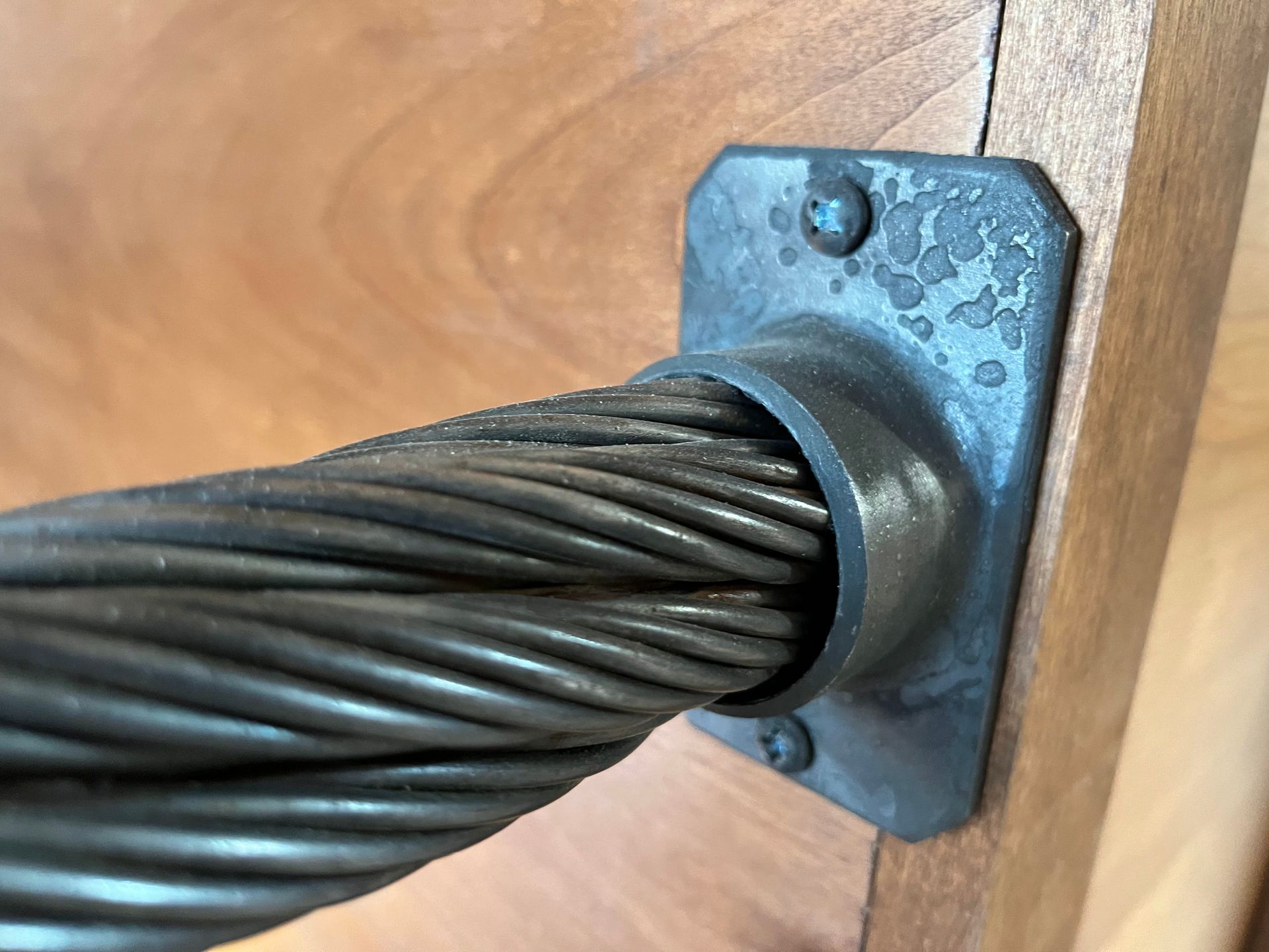 A close up of a metal cable attached to a wooden post