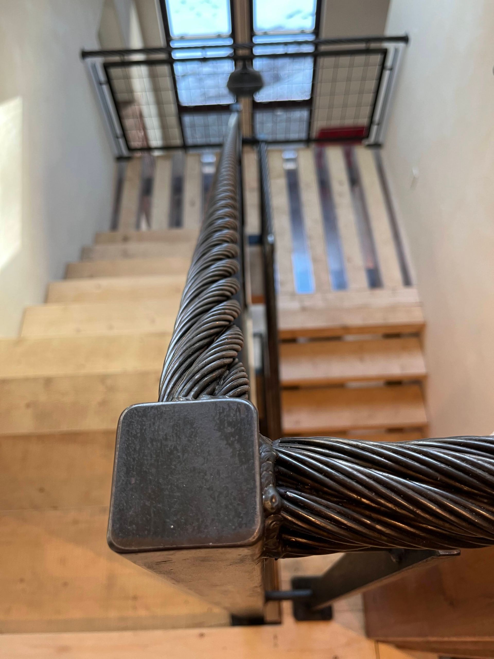 A close up of a metal railing on a wooden staircase.