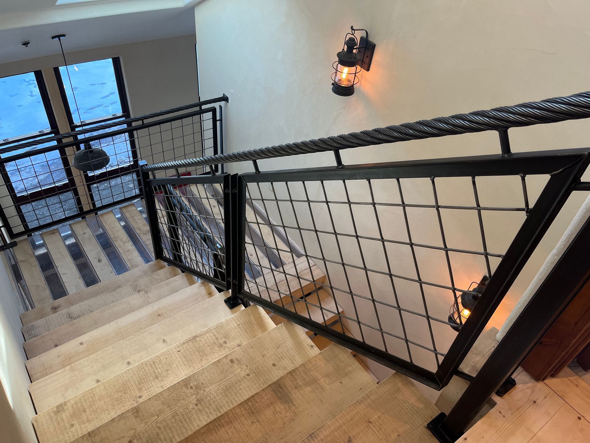A staircase with a black railing and a lantern on the wall