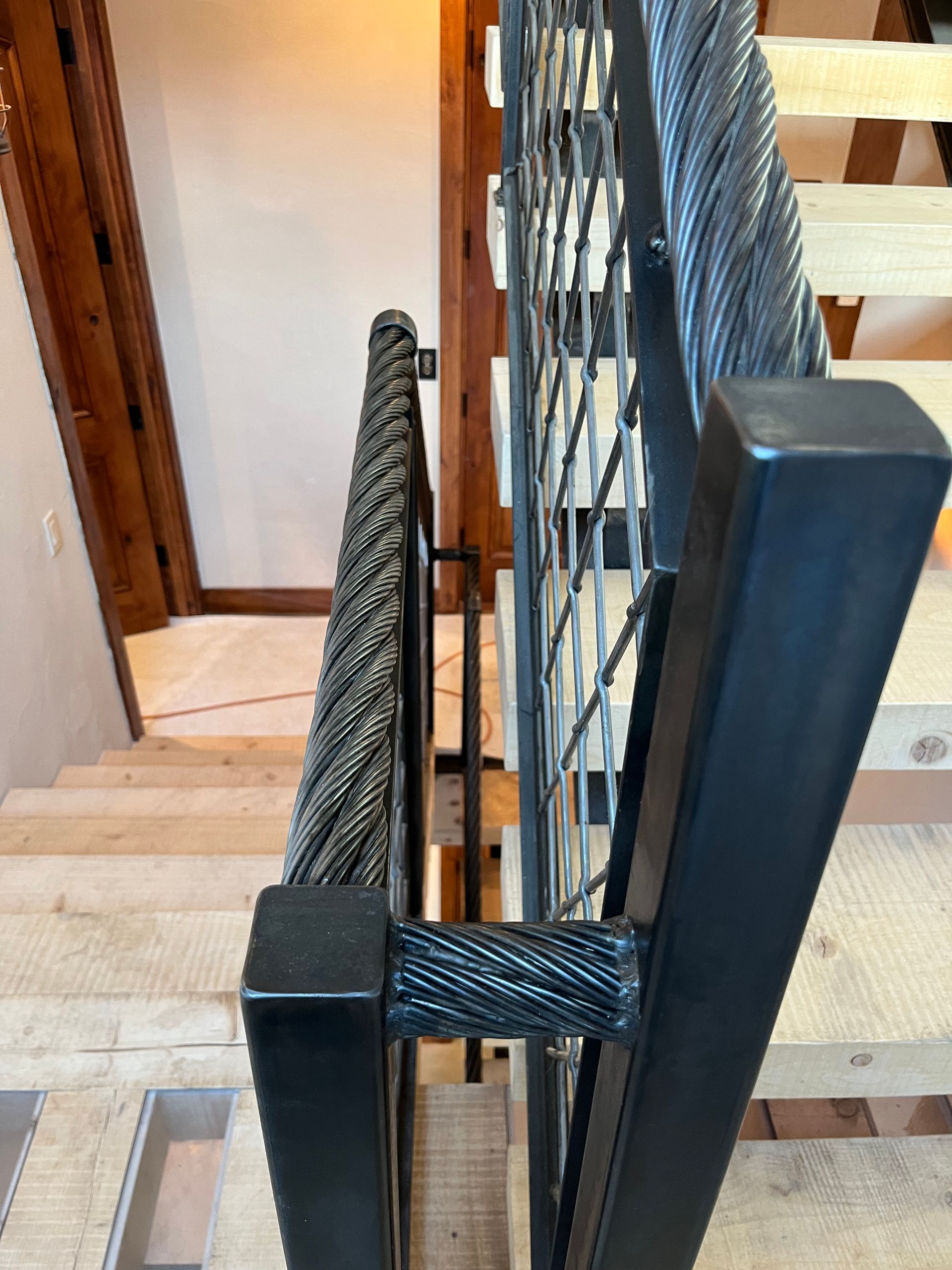 A close up of a metal railing on a wooden staircase.
