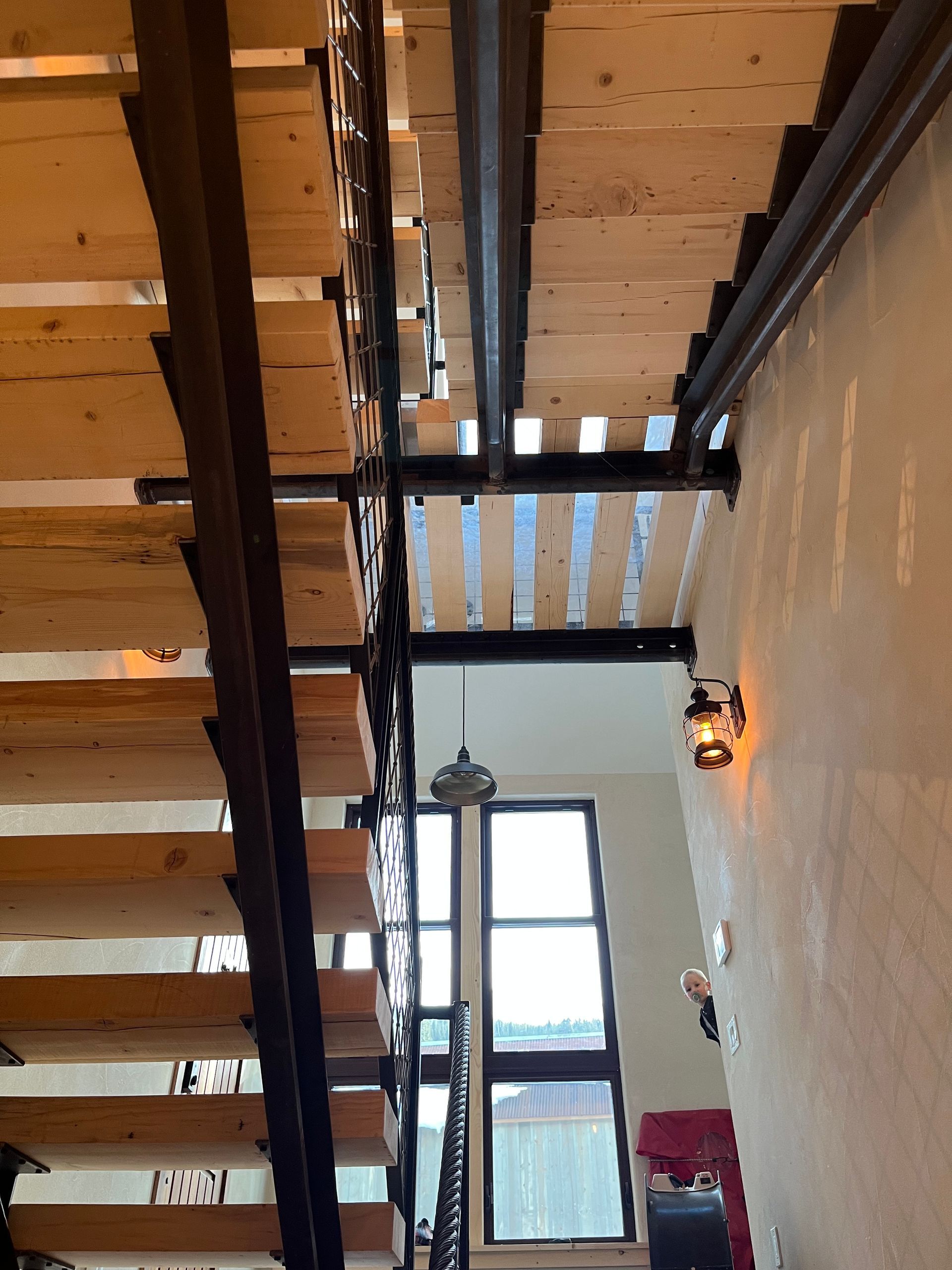 A wooden staircase with a metal railing and a window