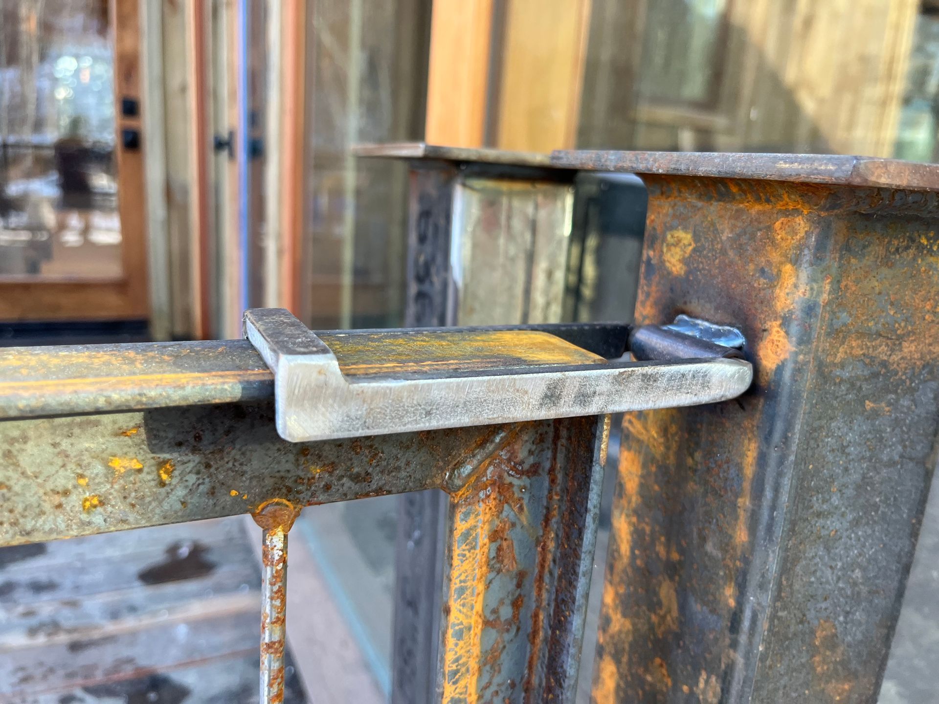 A close up of a rusty metal railing with a door in the background.