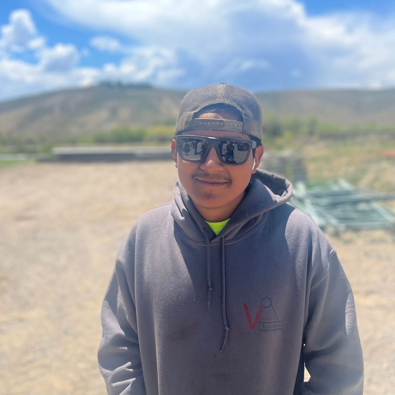 A man wearing sunglasses and a hat is standing in a field