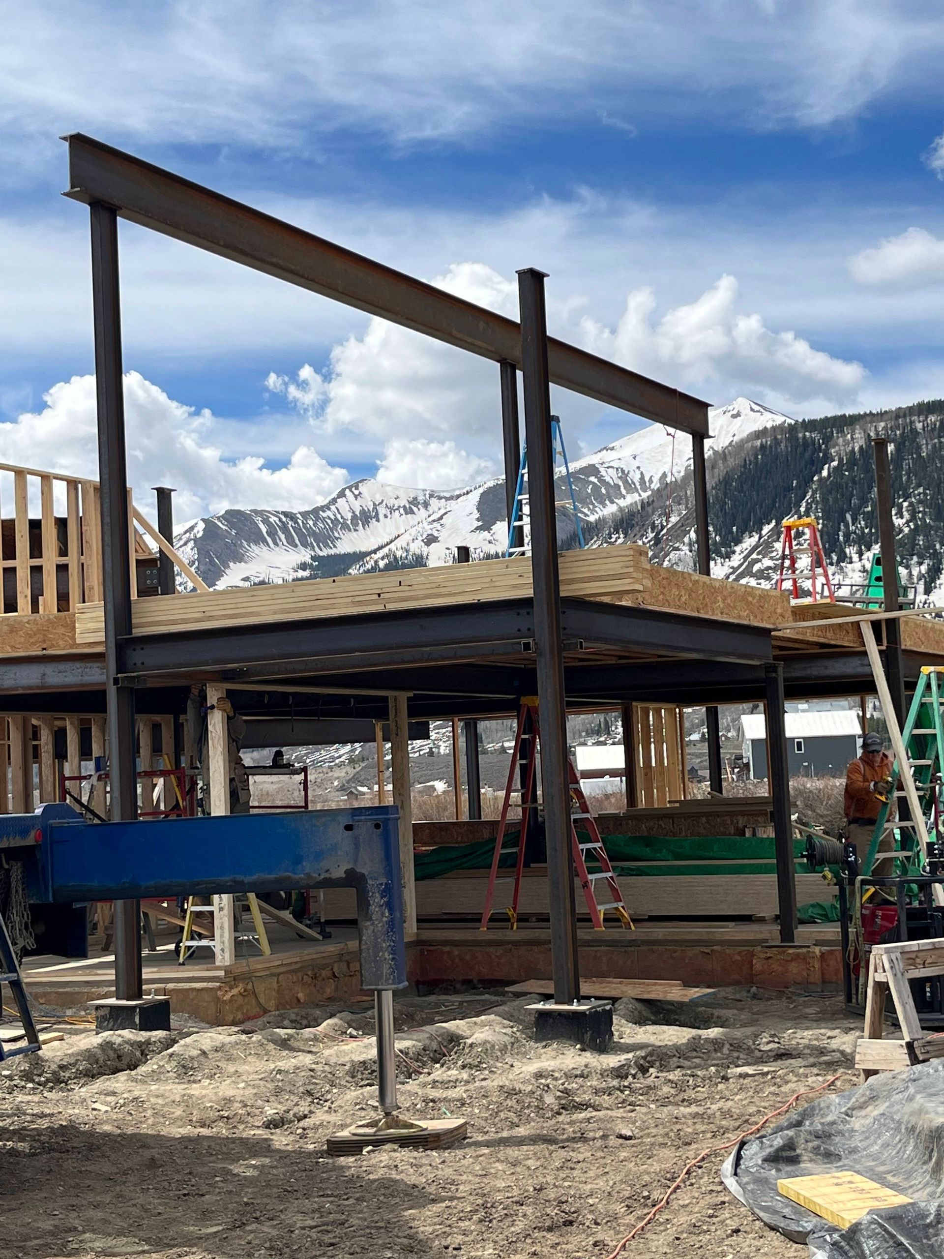 A large building is being built in the middle of a field with mountains in the background.