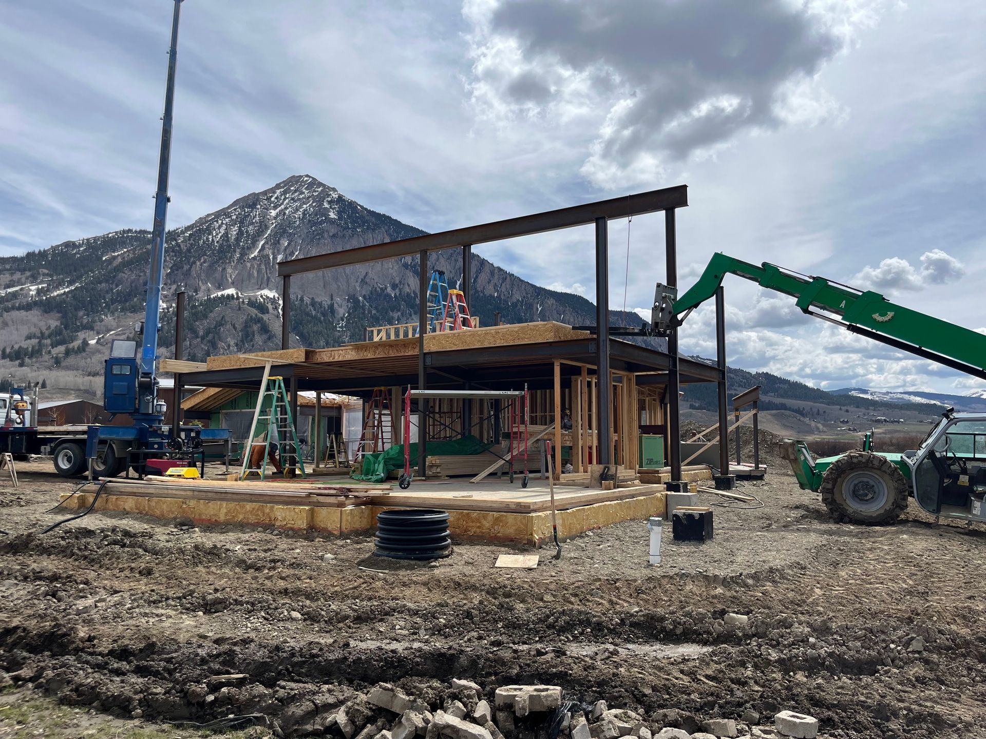 A building is being built in a dirt field with a mountain in the background.