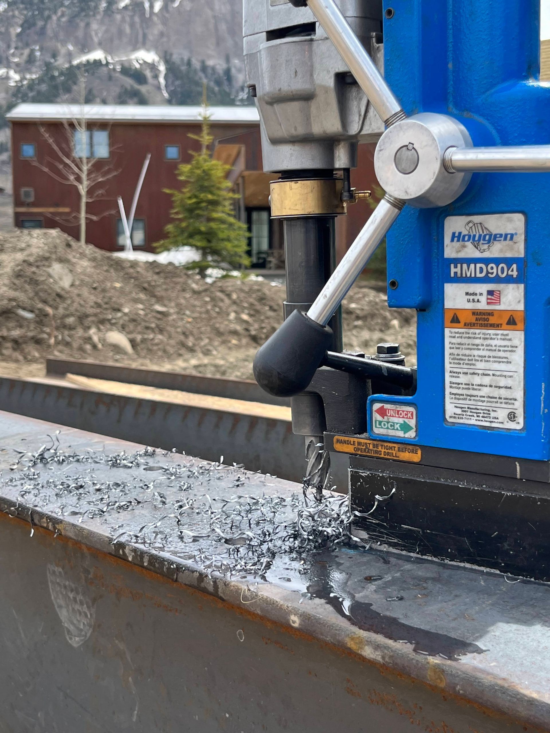 A blue machine is cutting a piece of metal