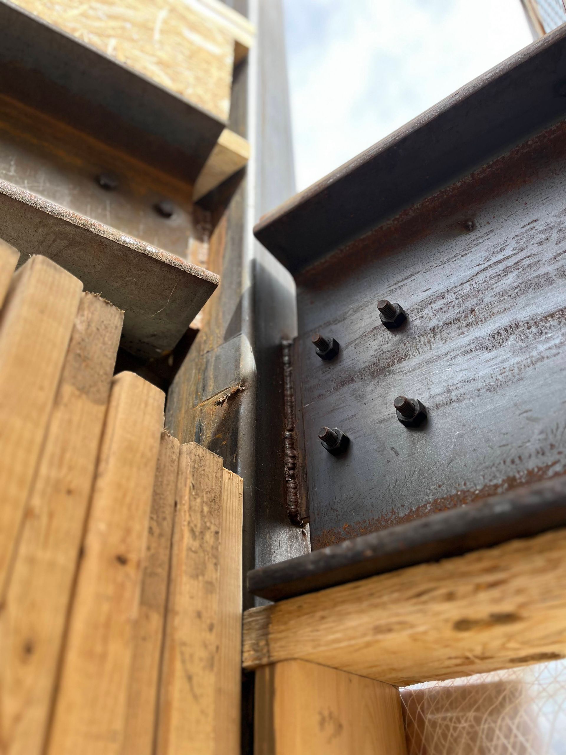 A close up of a metal beam between two wooden boards.
