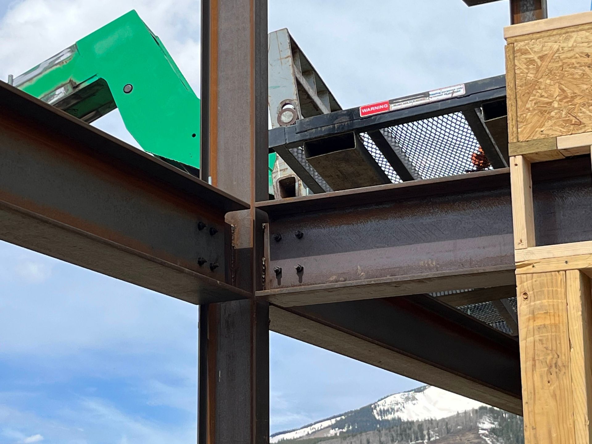 A green forklift is sitting on top of a metal structure