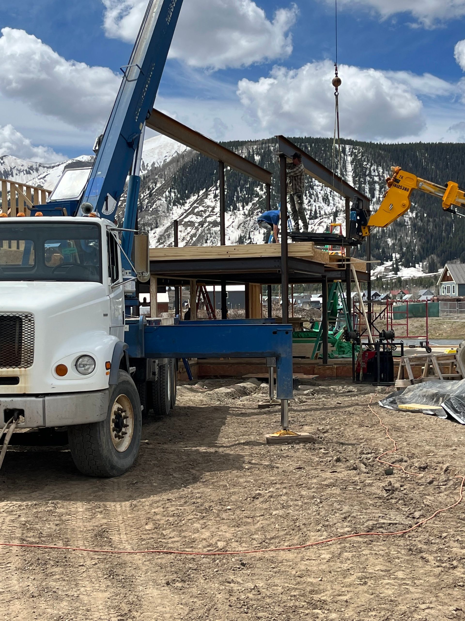 A truck with a crane attached to it is parked in a dirt field.
