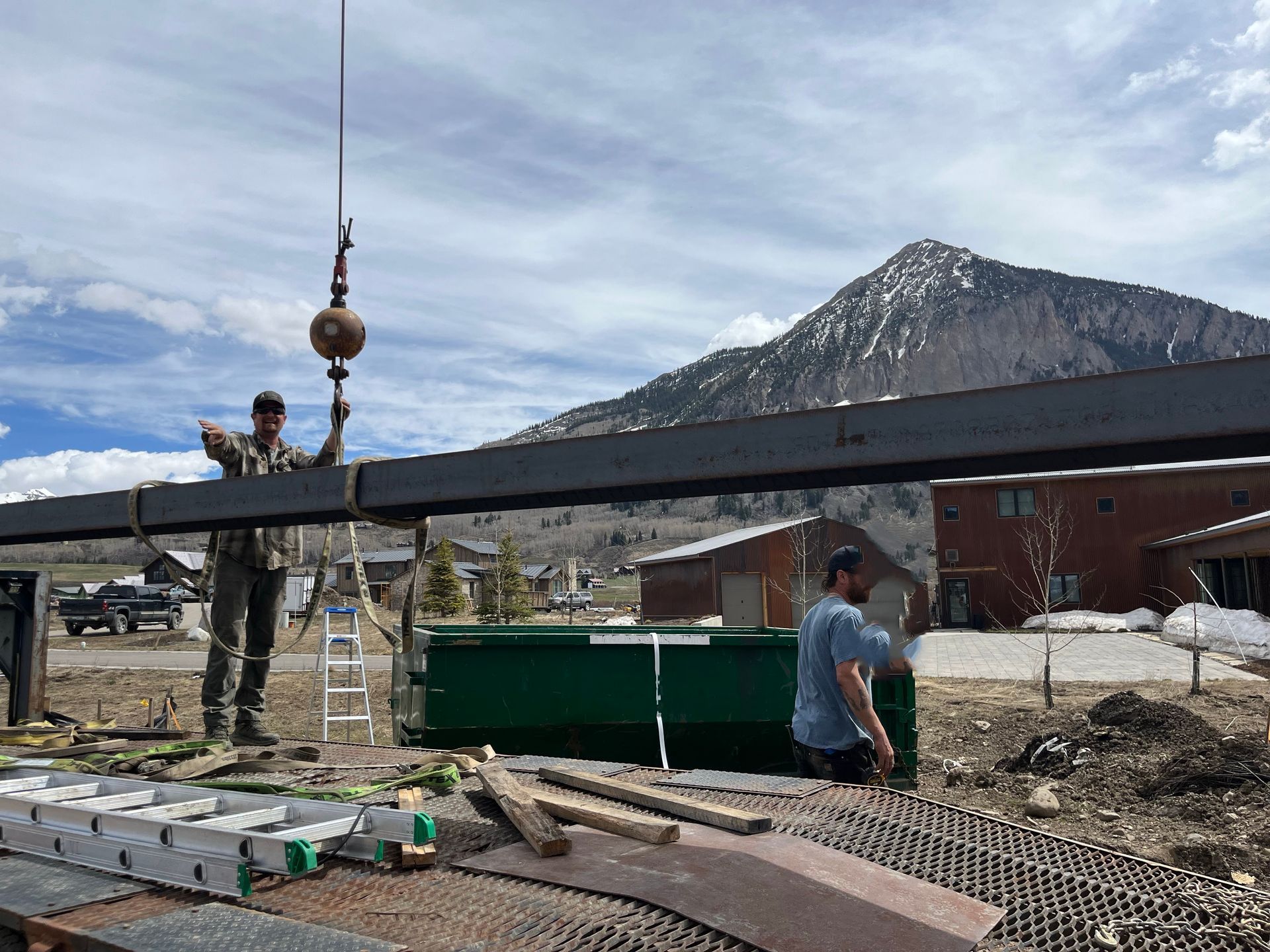 A man is using a crane to lift a large piece of metal.