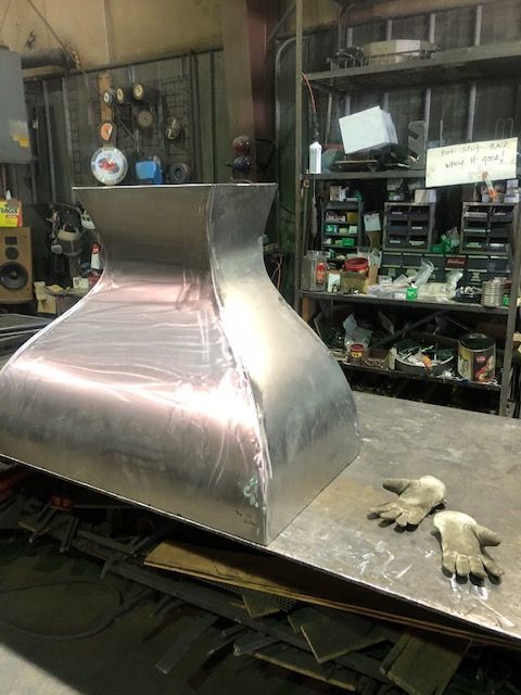 A large stainless steel object is sitting on a table in a workshop.
