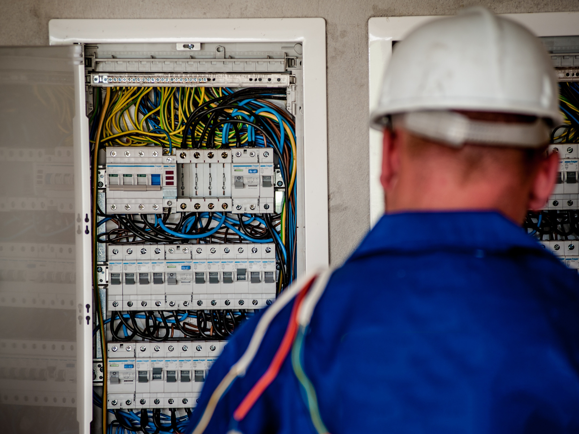 Electrician inspecting residential electrical panel with wiring, breakers, and circuit components.