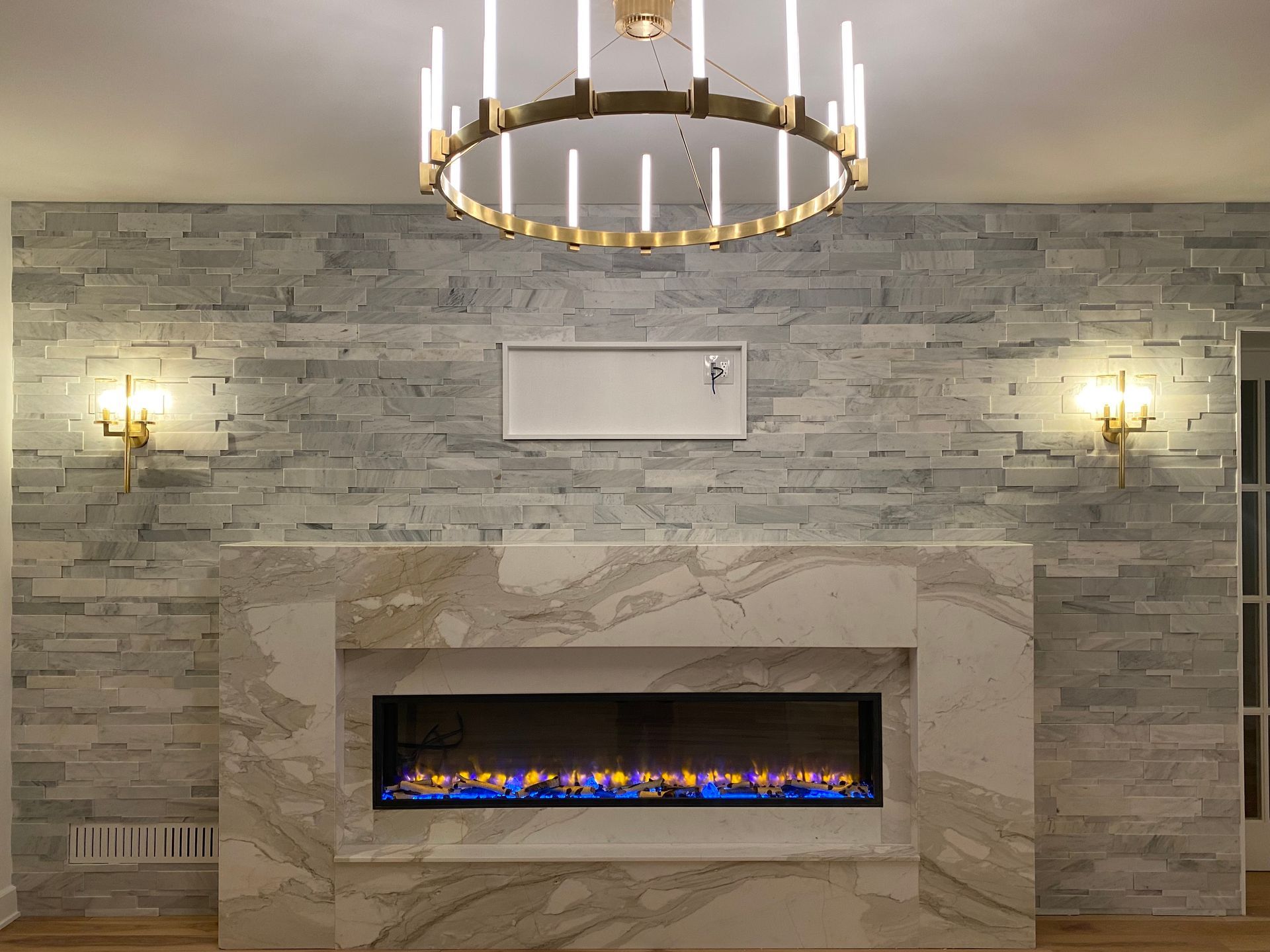 Modern living room with chandelier and wall sconces professionally installed for custom lighting design.