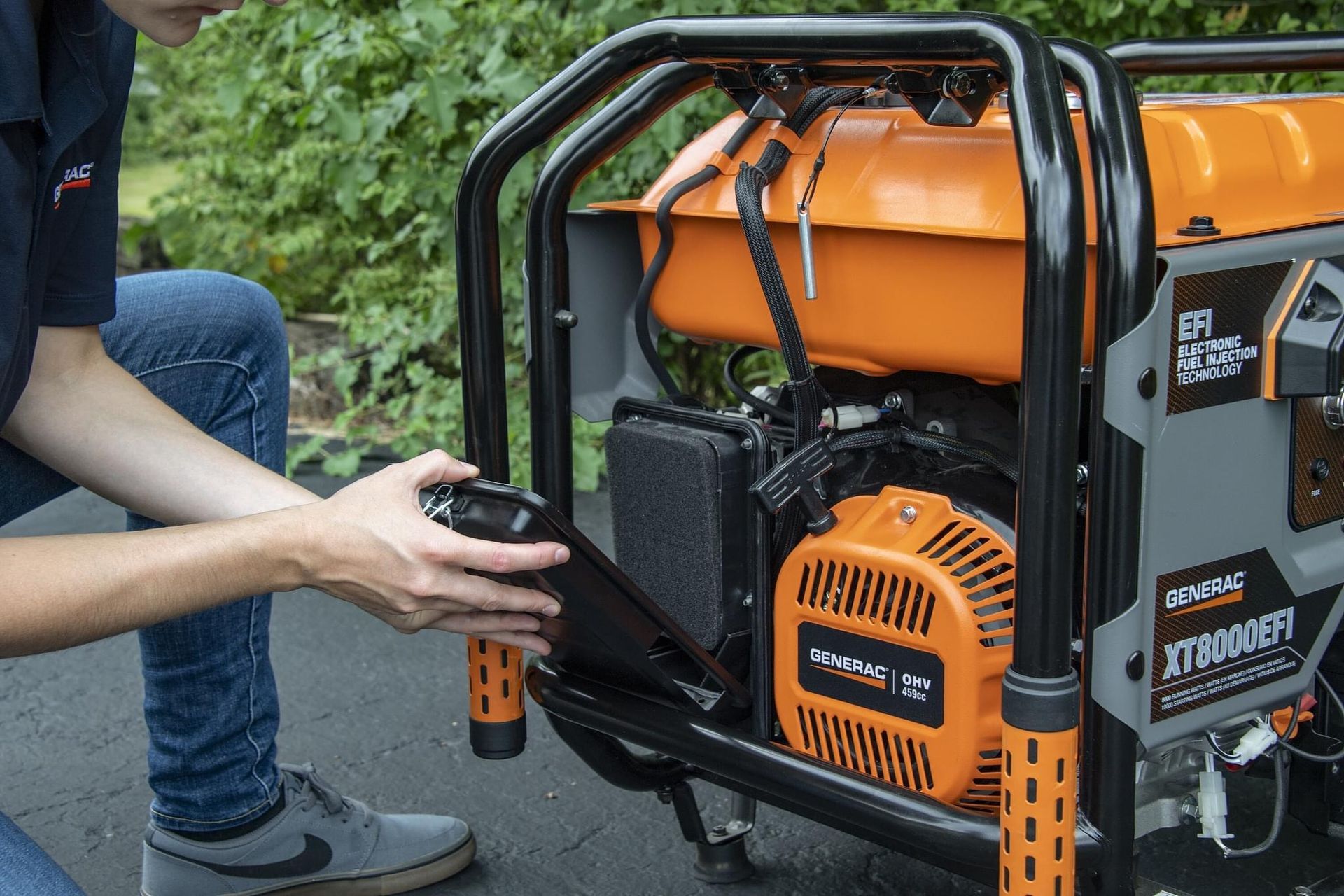 Person adjusting a black panel on an orange and black portable generator outdoors.