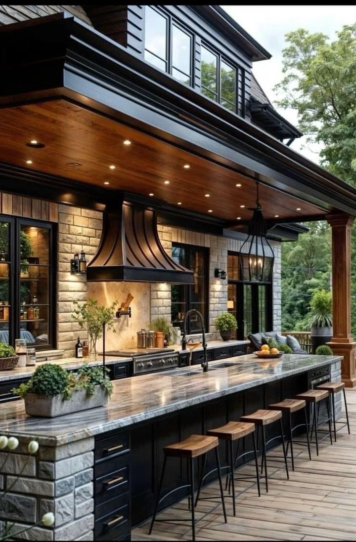 Outdoor kitchen with stone, wood, black cabinets, and a long countertop with stools.